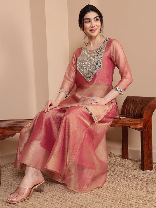 Woman wearing a pink saree with silver embroidery sitting on a wooden bench.