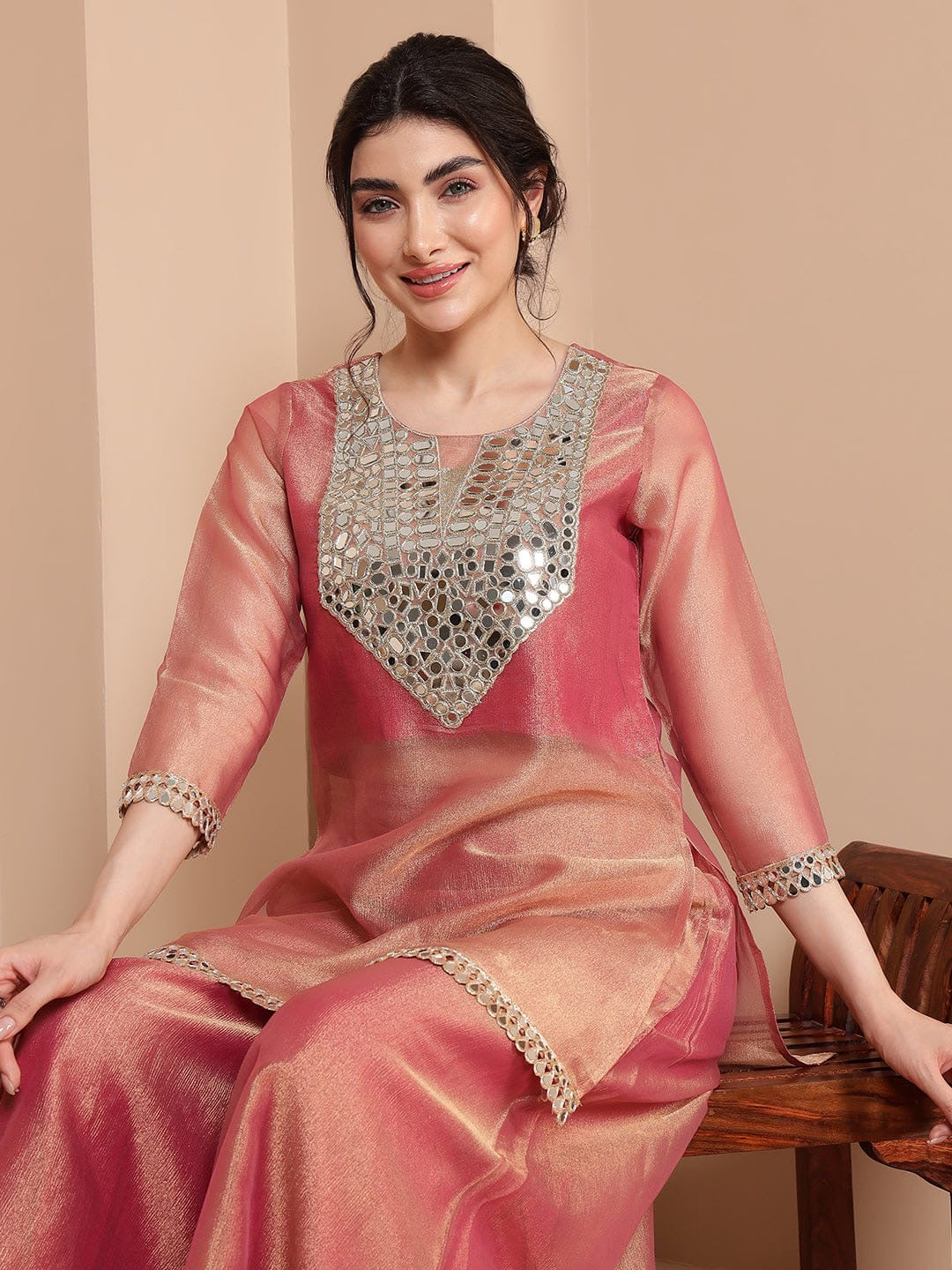 Woman wearing a pink traditional outfit with silver embellishments on a beige background
