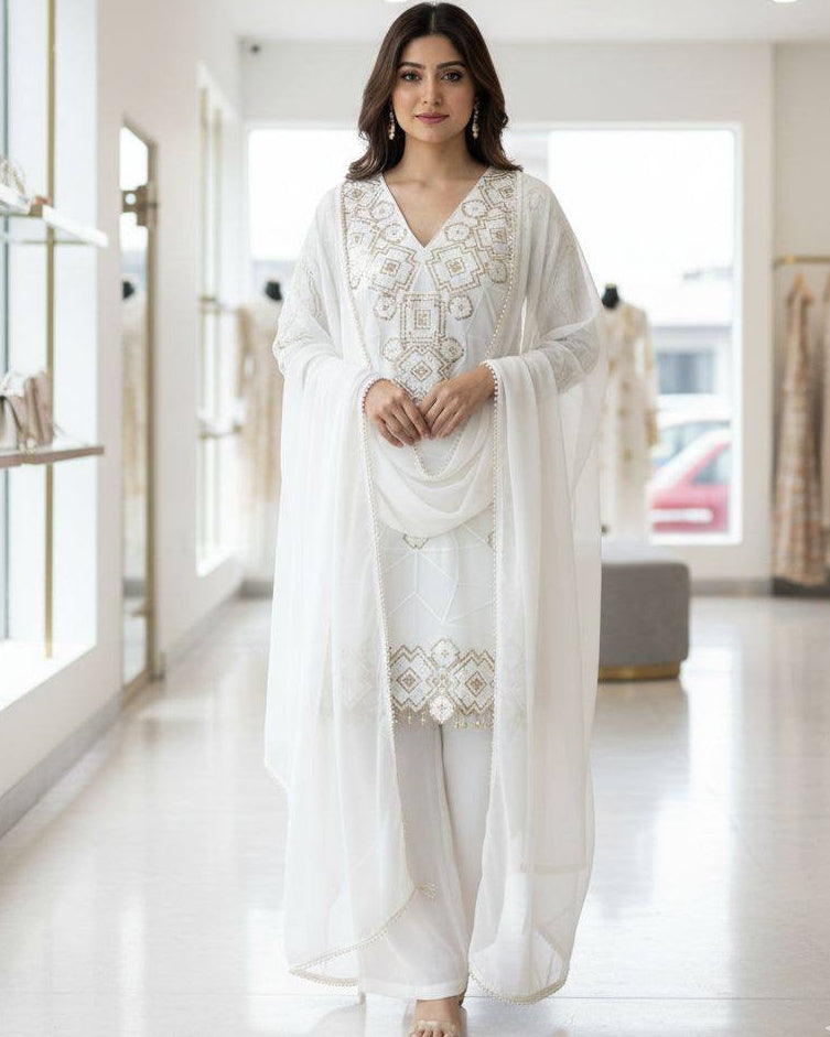 Woman in a white traditional outfit standing in a modern interior setting