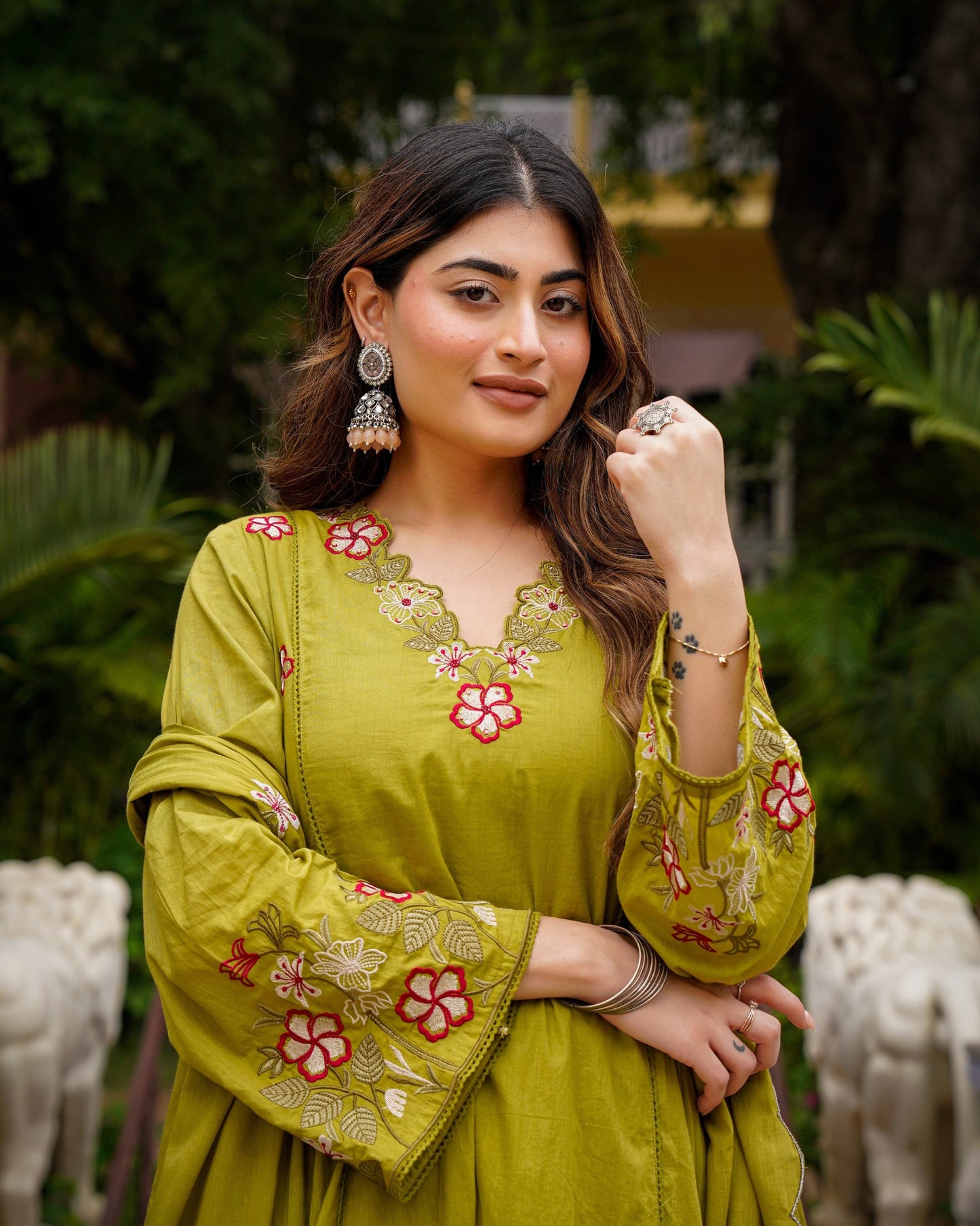 Woman wearing a green embroidered dress with a blurred natural background
