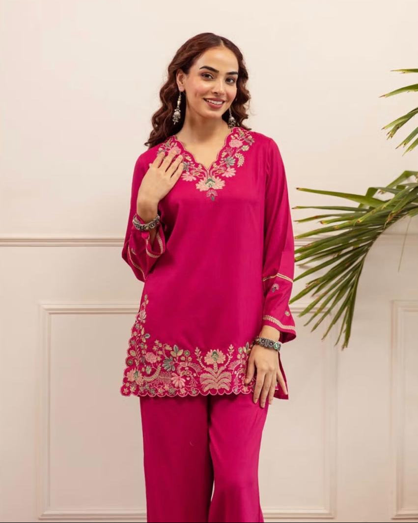 Woman wearing a pink embroidered outfit with a neutral background