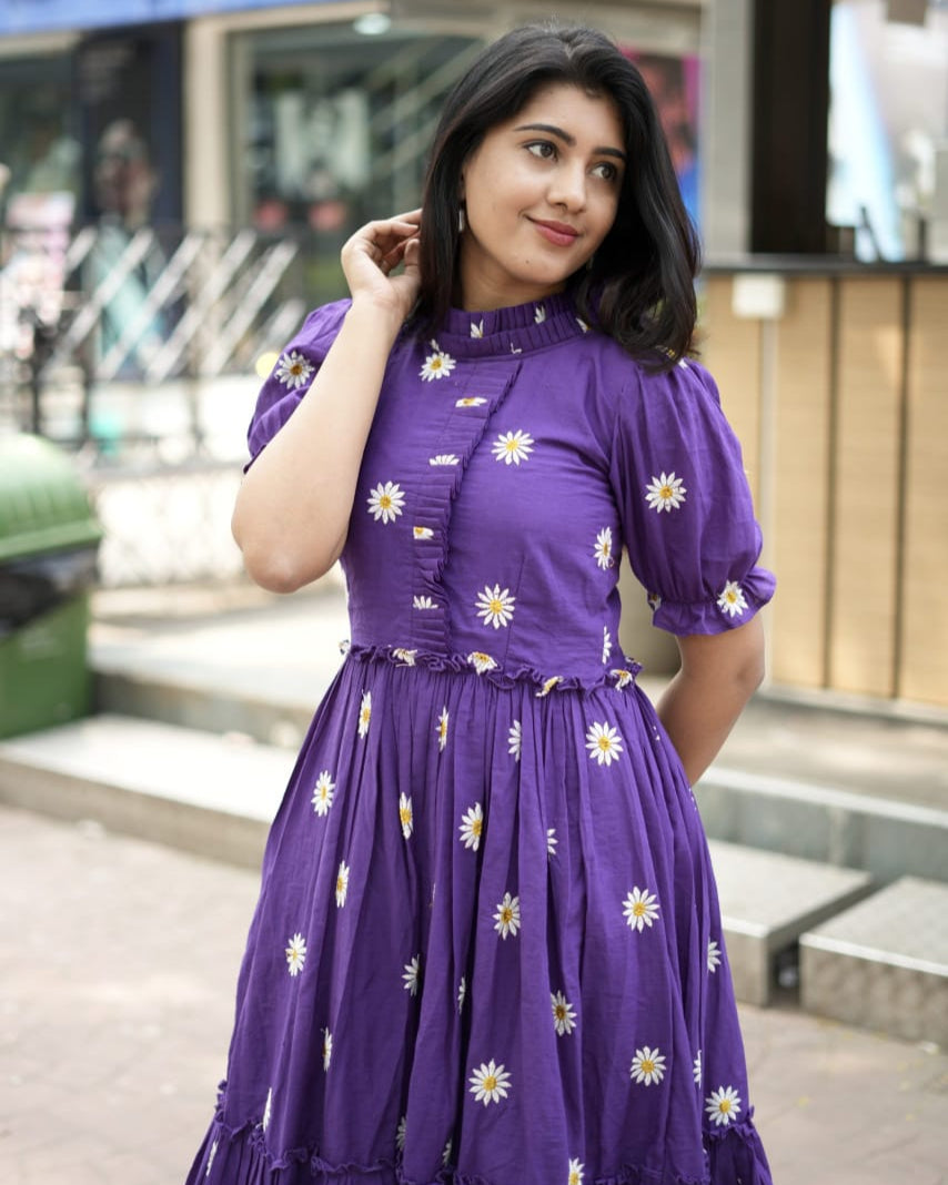 Woman wearing a purple dress with floral patterns in an urban setting