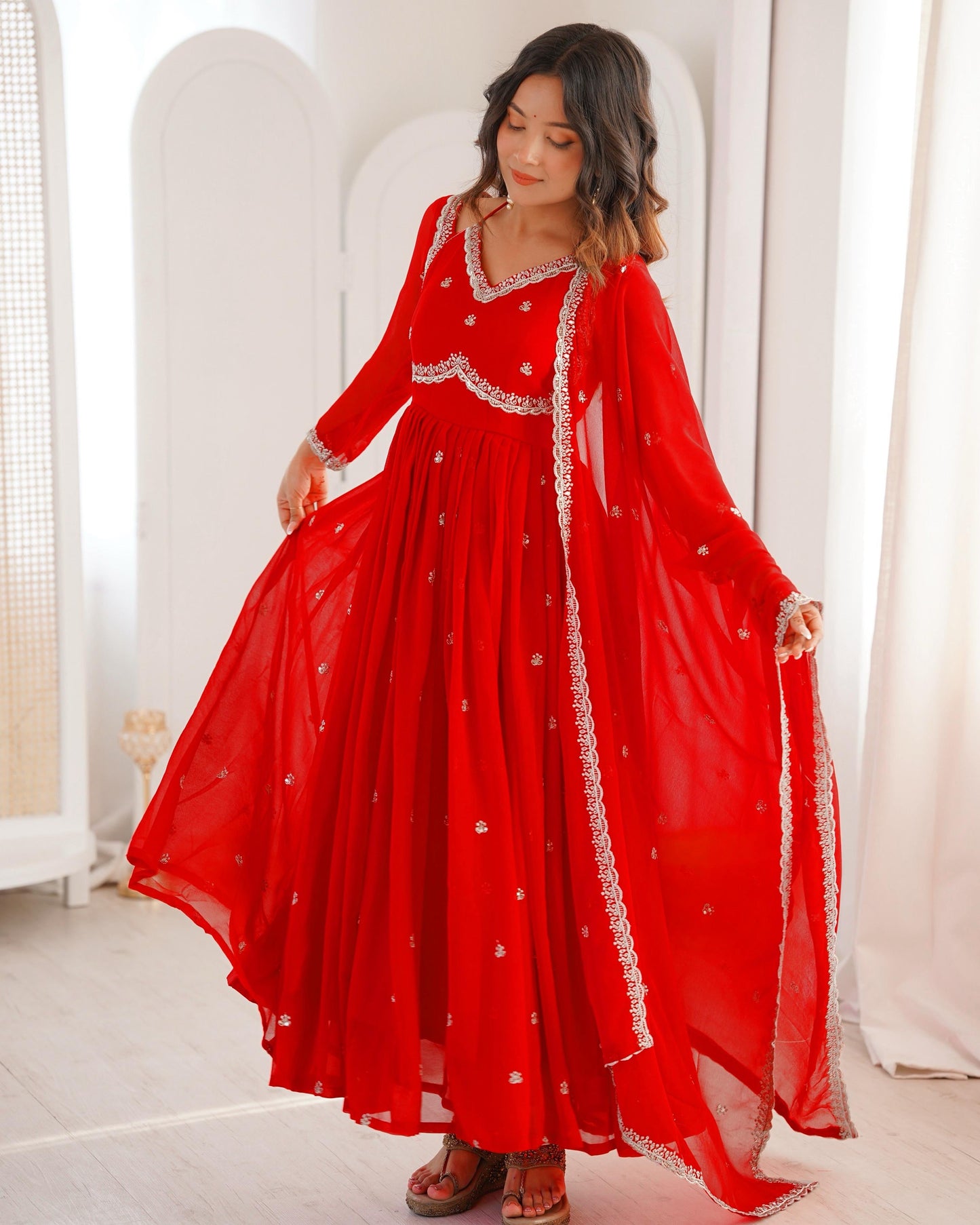Woman wearing a red traditional outfit with white embroidery in a minimalistic setting