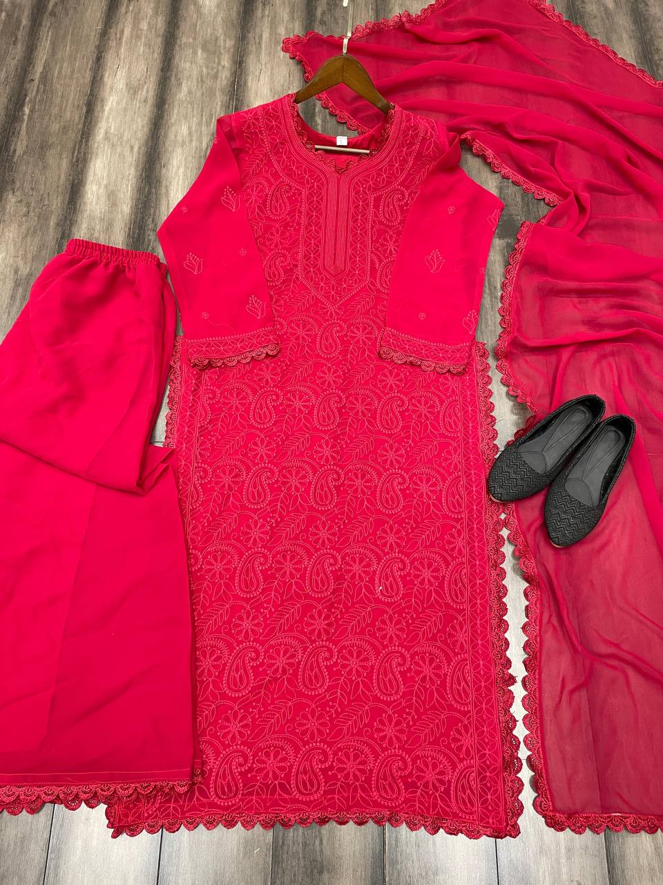 Red embroidered outfit with a hanger, skirt, and shoes on a wooden surface