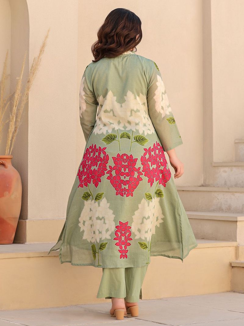 Woman wearing a light green dress with pink floral patterns in an outdoor setting.