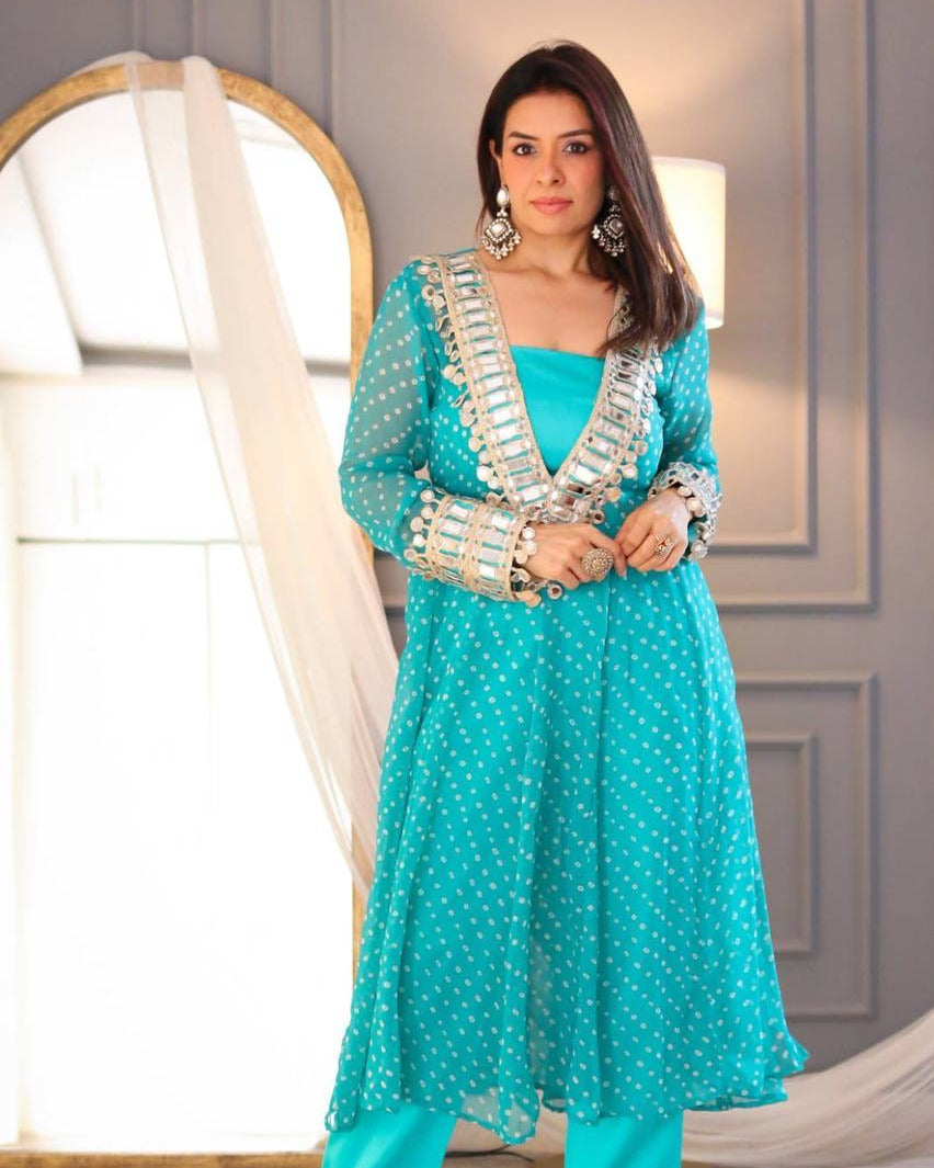 Woman wearing a turquoise traditional outfit with silver details in a well-lit room.