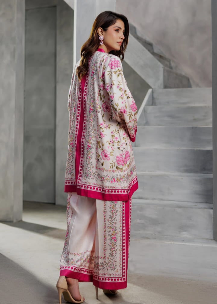 Woman in a traditional outfit with floral patterns standing in a modern architectural setting.