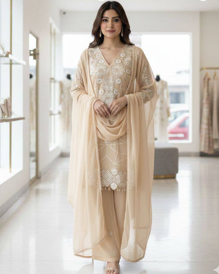 Woman in a beige outfit with floral patterns standing in a well-lit indoor setting.
