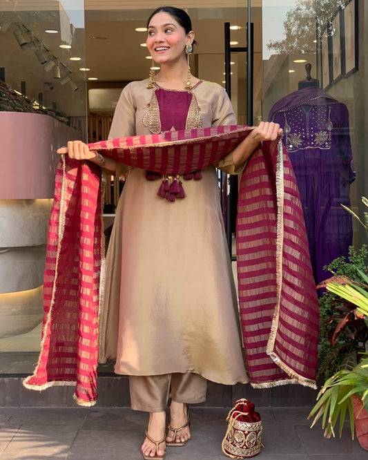Woman holding a red and gold saree in front of a store entrance