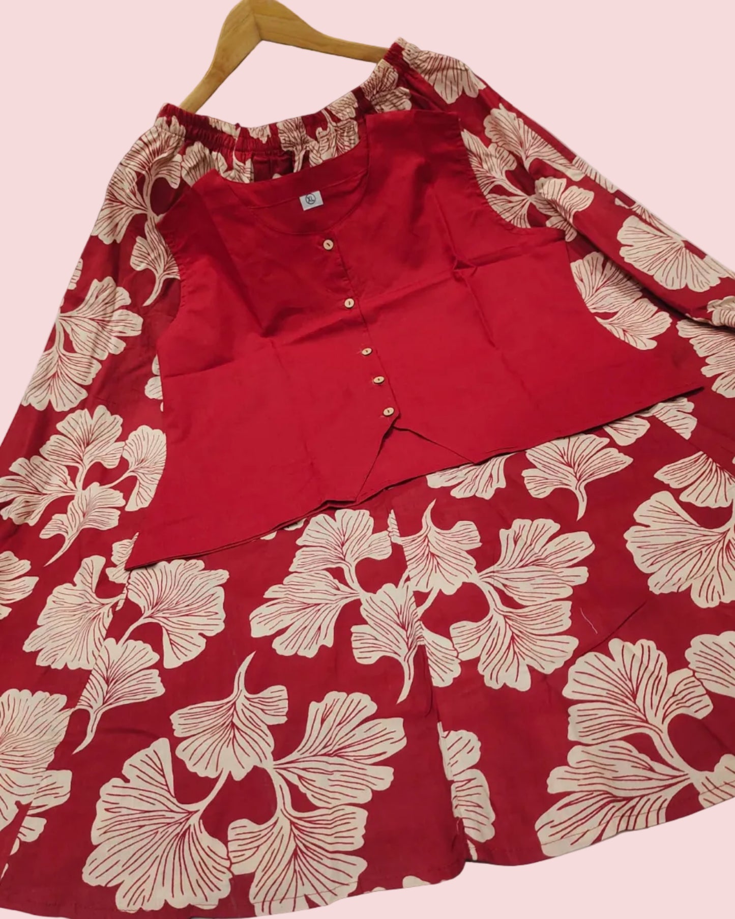 Red floral dress with a red shirt underneath on a white floor.