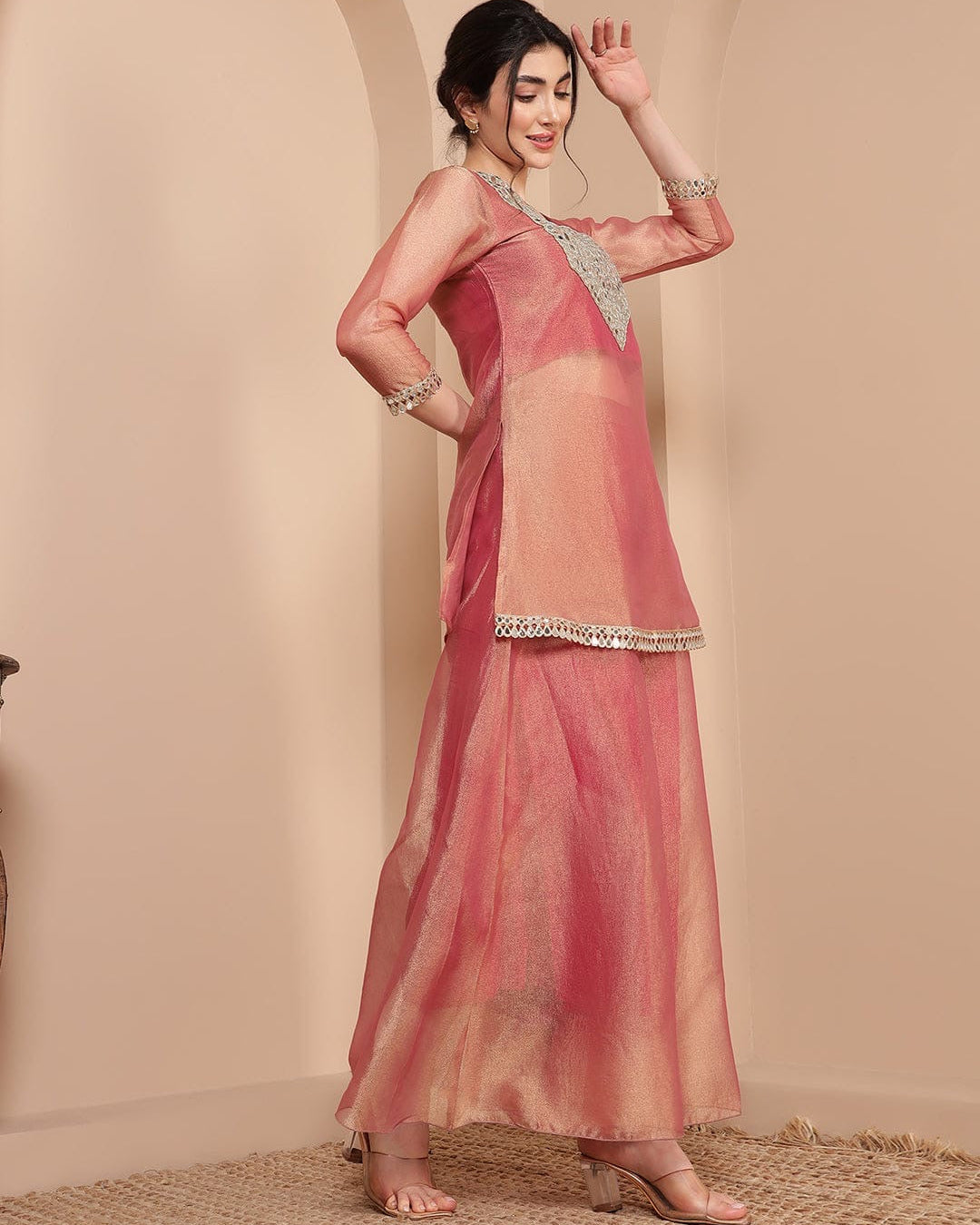 Woman wearing a pink saree with a plain background