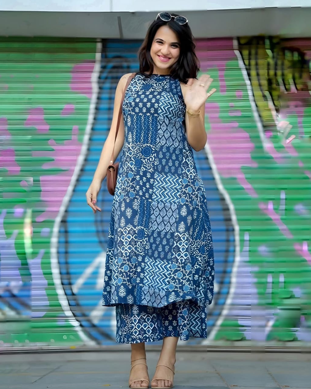 Woman in a blue patterned dress standing in front of a colorful shutter.