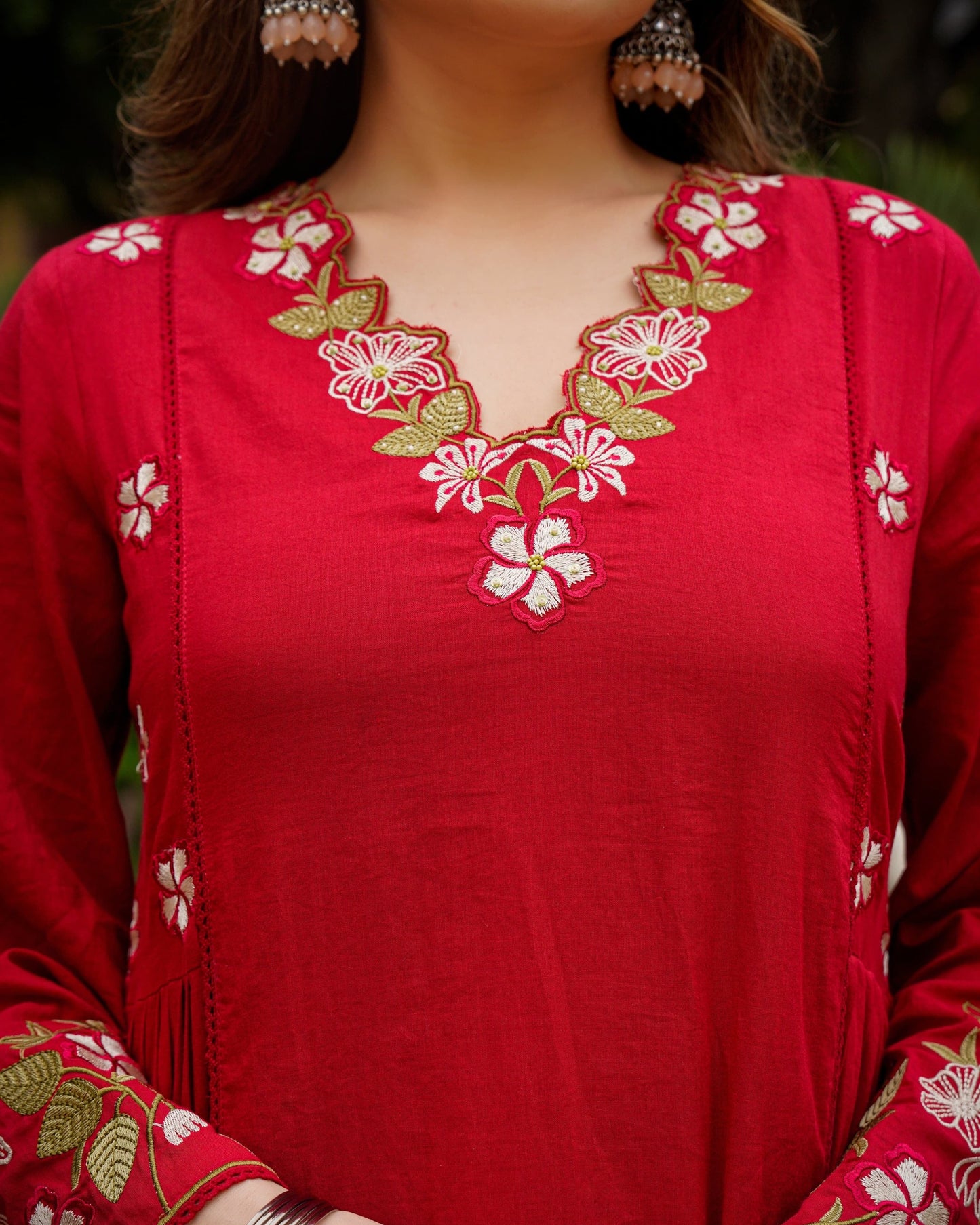 Red embroidered top with floral patterns on a blurred background