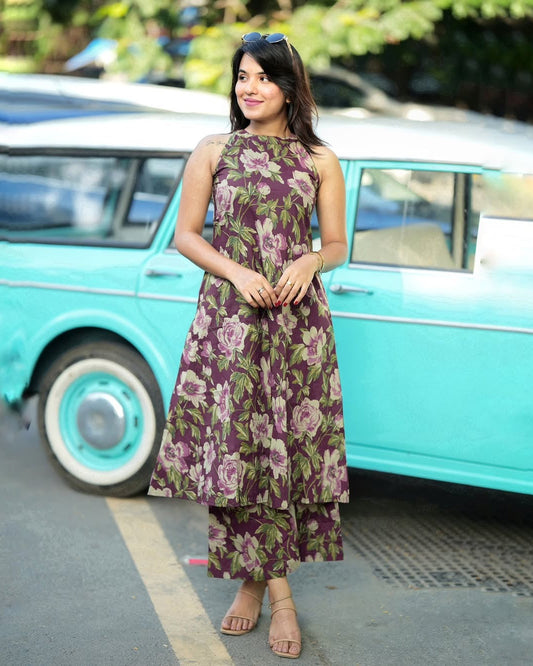 Woman in a floral dress standing in front of a turquoise vintage car.