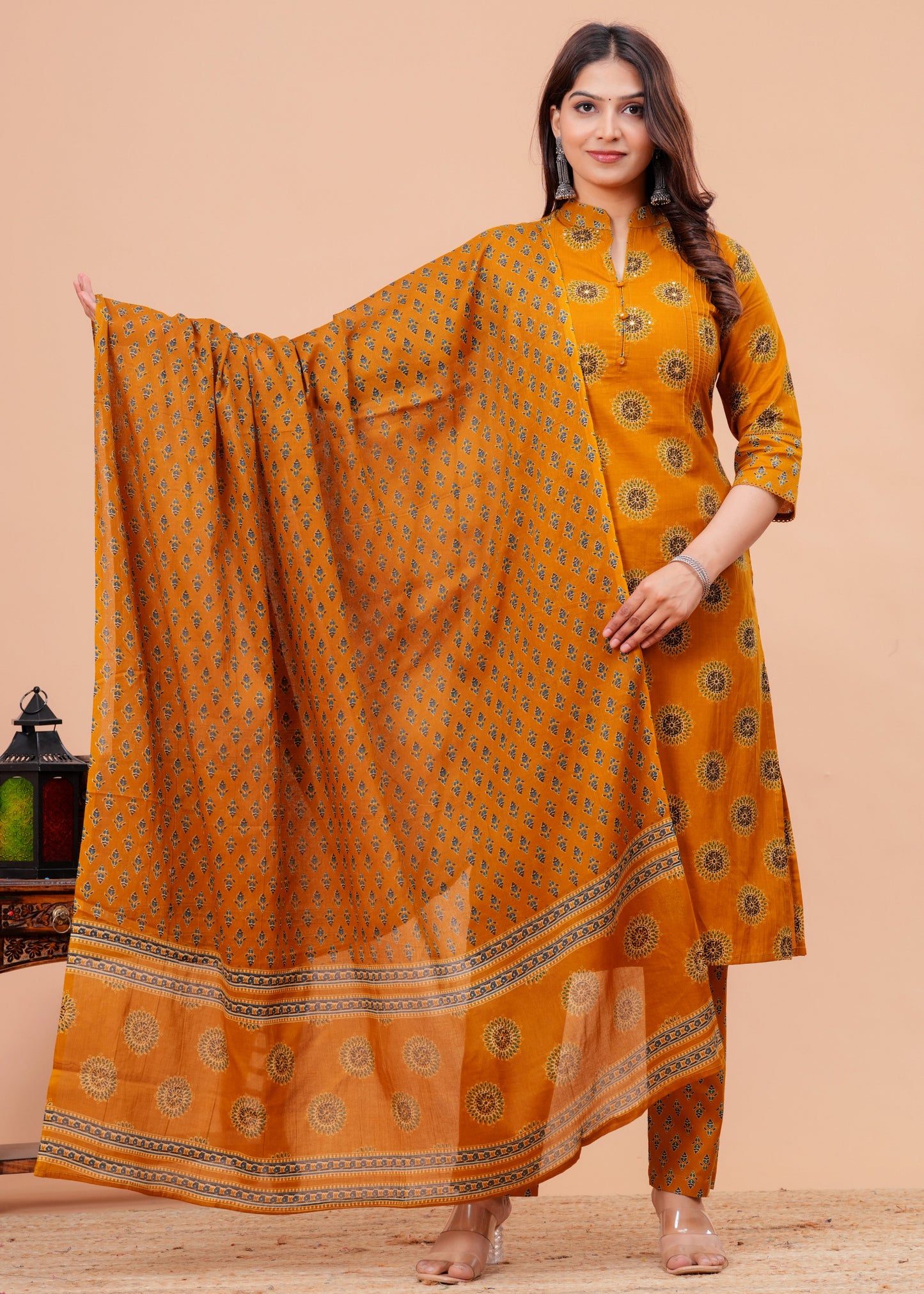 Woman wearing a mustard yellow traditional outfit with a matching dupatta on a beige background