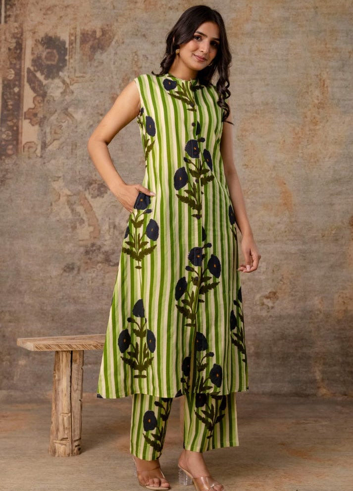 Woman wearing a green floral dress standing against a textured wall.