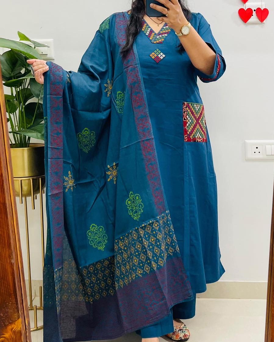 Person wearing a blue traditional outfit with intricate patterns indoors.