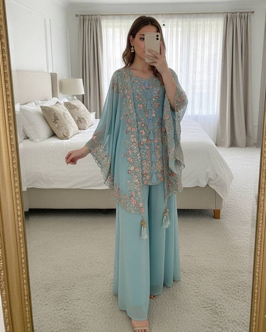 Woman taking a mirror selfie wearing a light blue outfit with floral patterns in a bedroom.