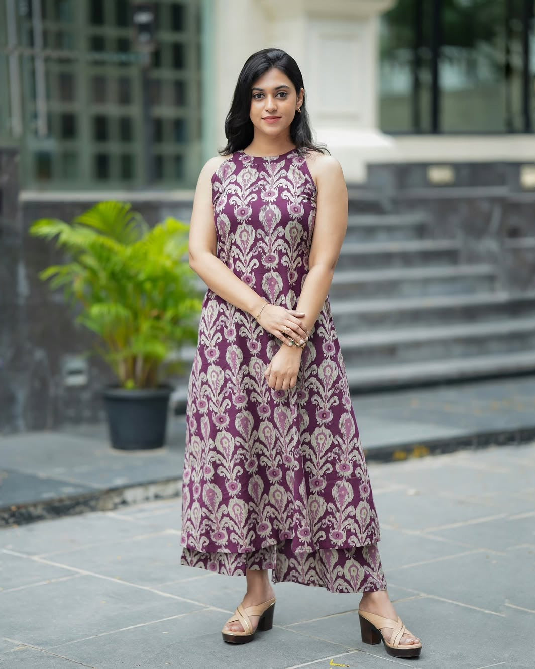 Woman wearing a purple patterned dress standing outdoors.