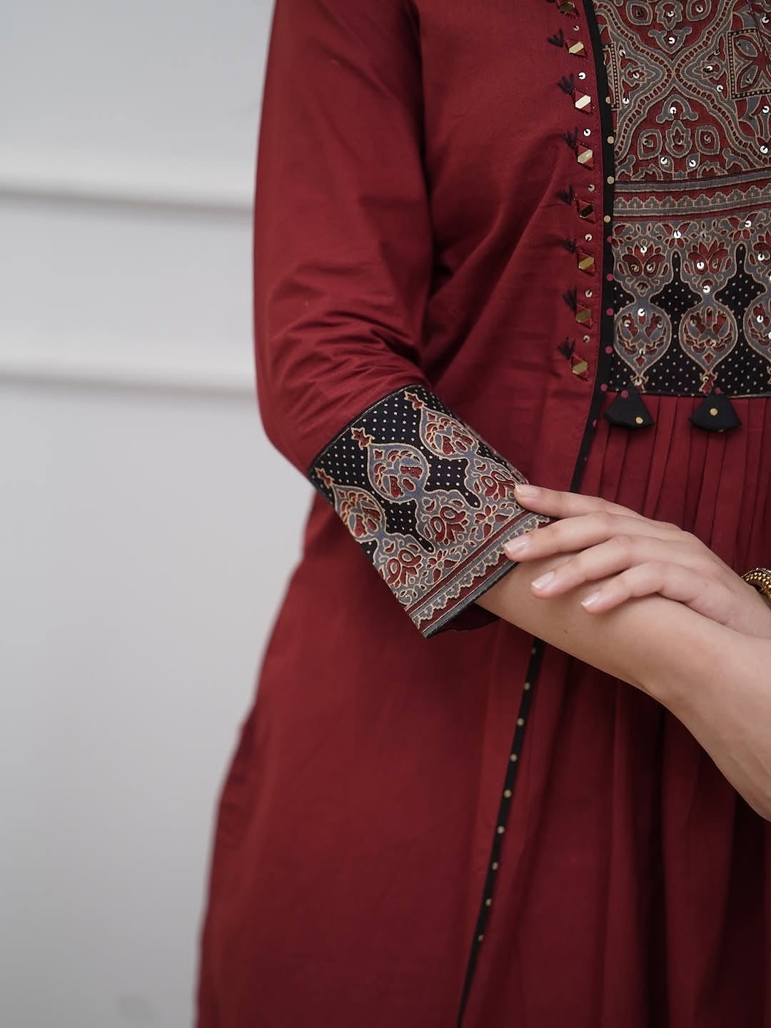 Maroon traditional outfit with intricate patterns on a plain background