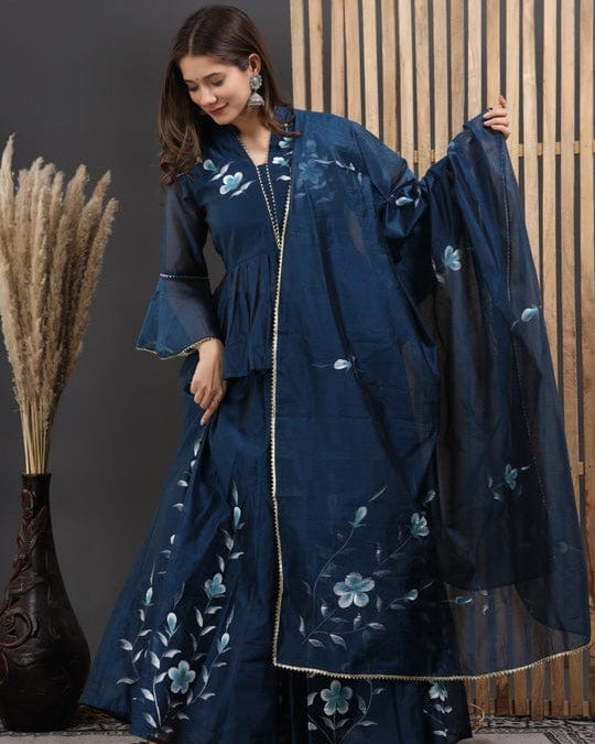 Woman wearing a dark blue embroidered outfit with a matching dupatta against a neutral background
