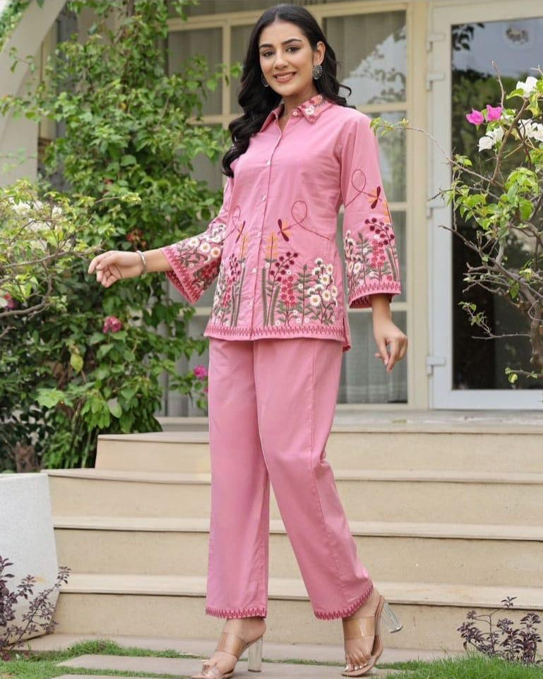 Woman in a pink traditional outfit standing outdoors on steps.