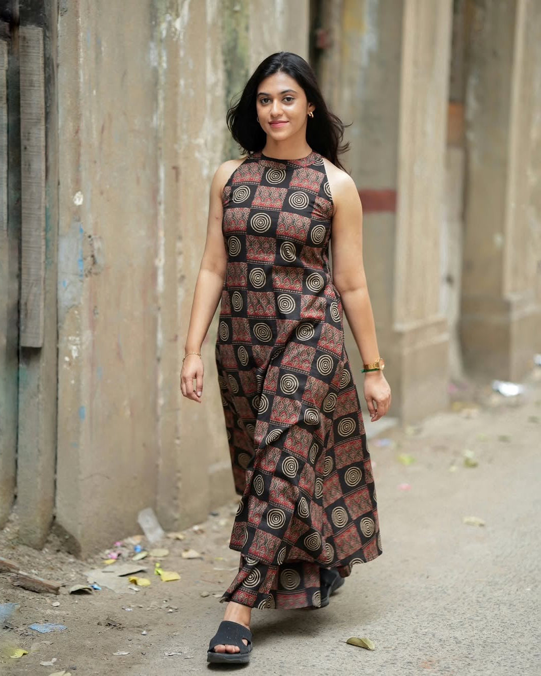 Woman wearing a patterned dress standing in an alleyway.