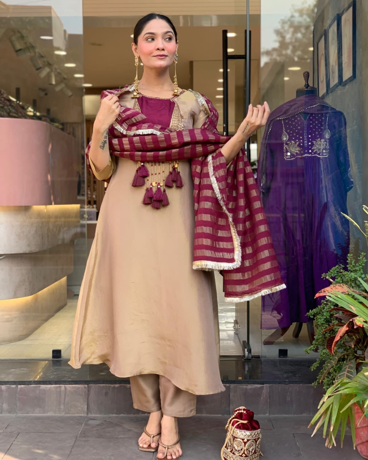 Woman in traditional attire holding a scarf with a store interior in the background