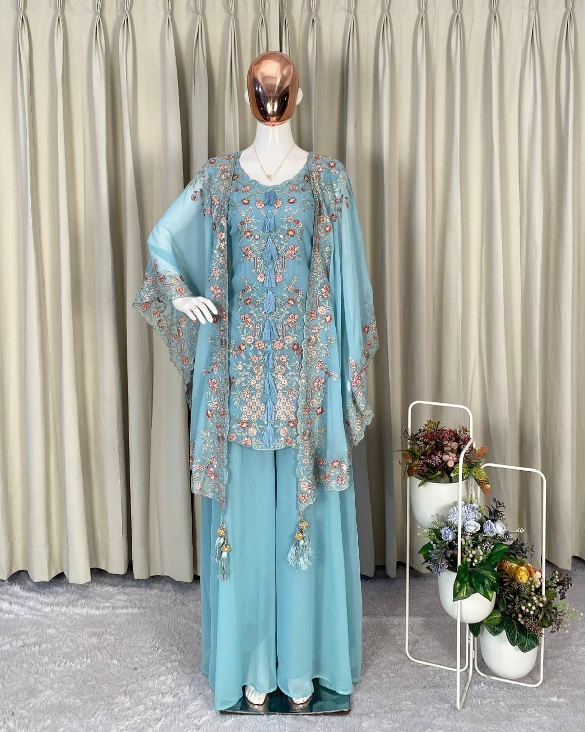 Mannequin wearing a light blue floral outfit with a beige curtain background