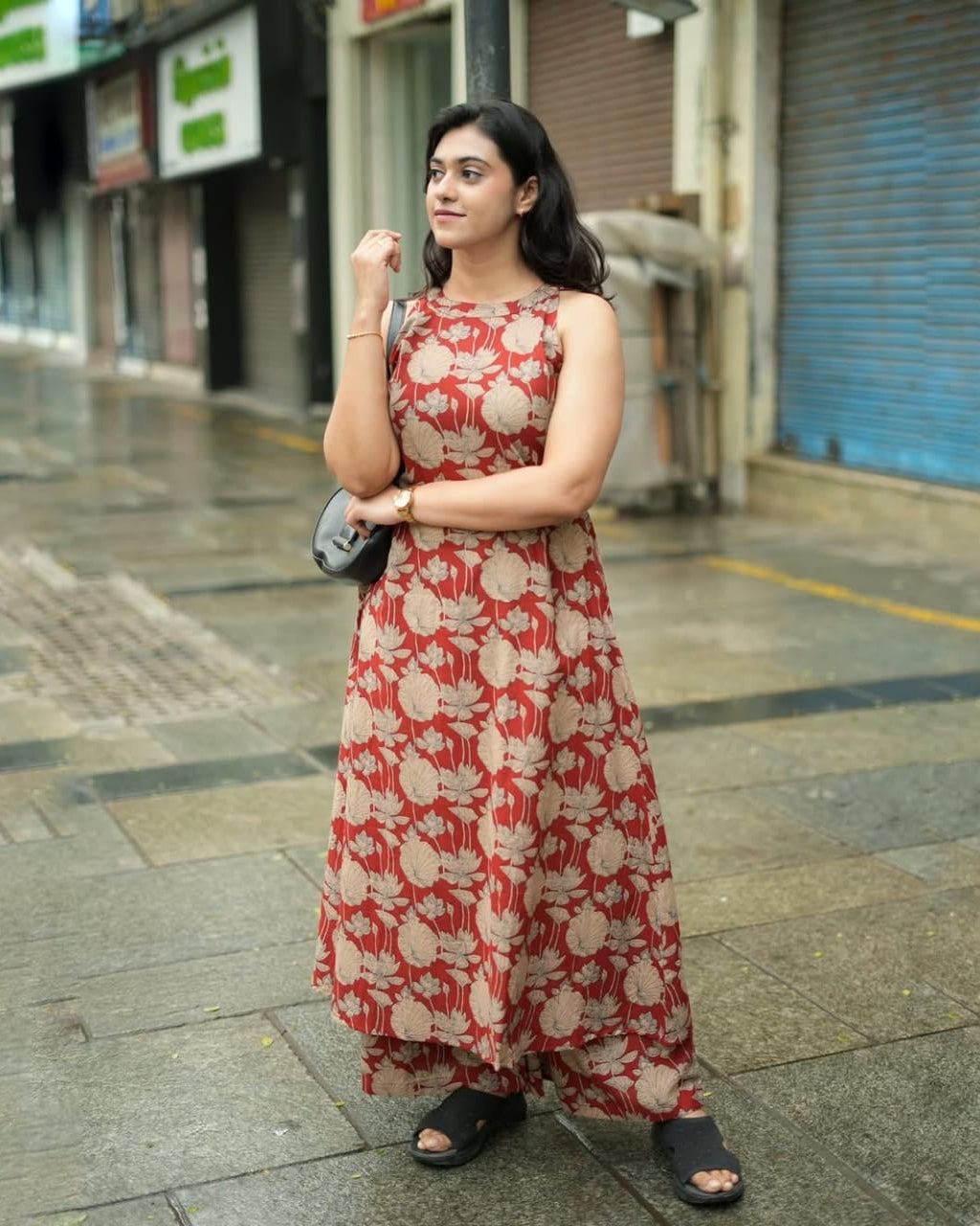 Woman in a red floral dress standing on a city street.