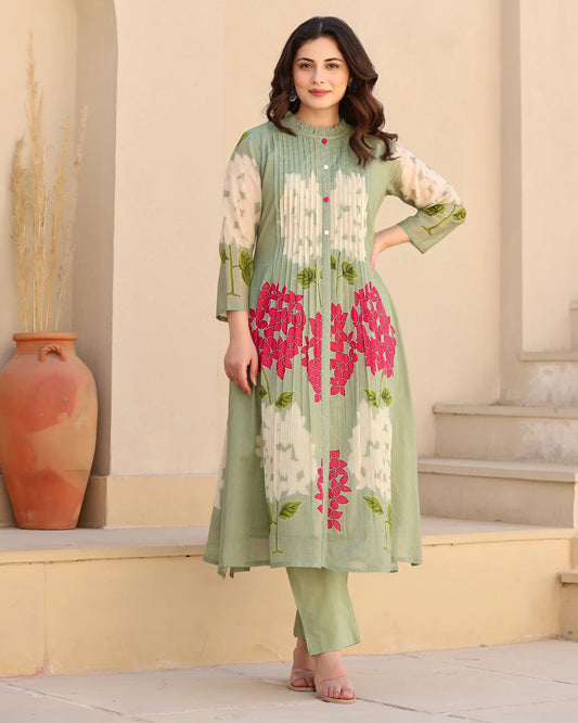 Woman wearing a green floral dress standing outdoors with a neutral background