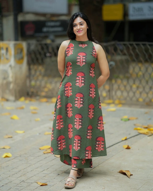 Woman wearing a green dress with red floral pattern on a street.