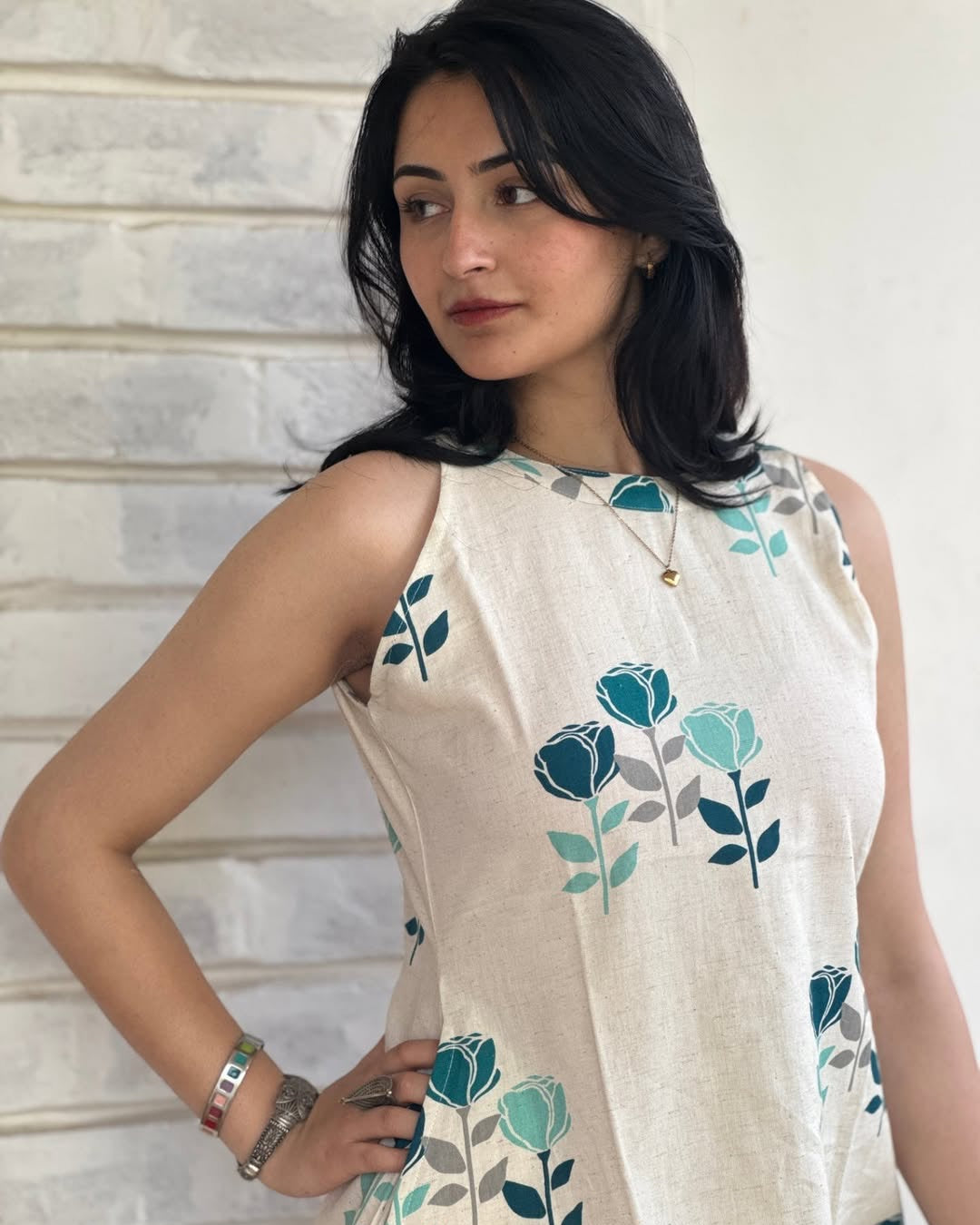 Woman wearing a sleeveless top with floral patterns against a neutral background