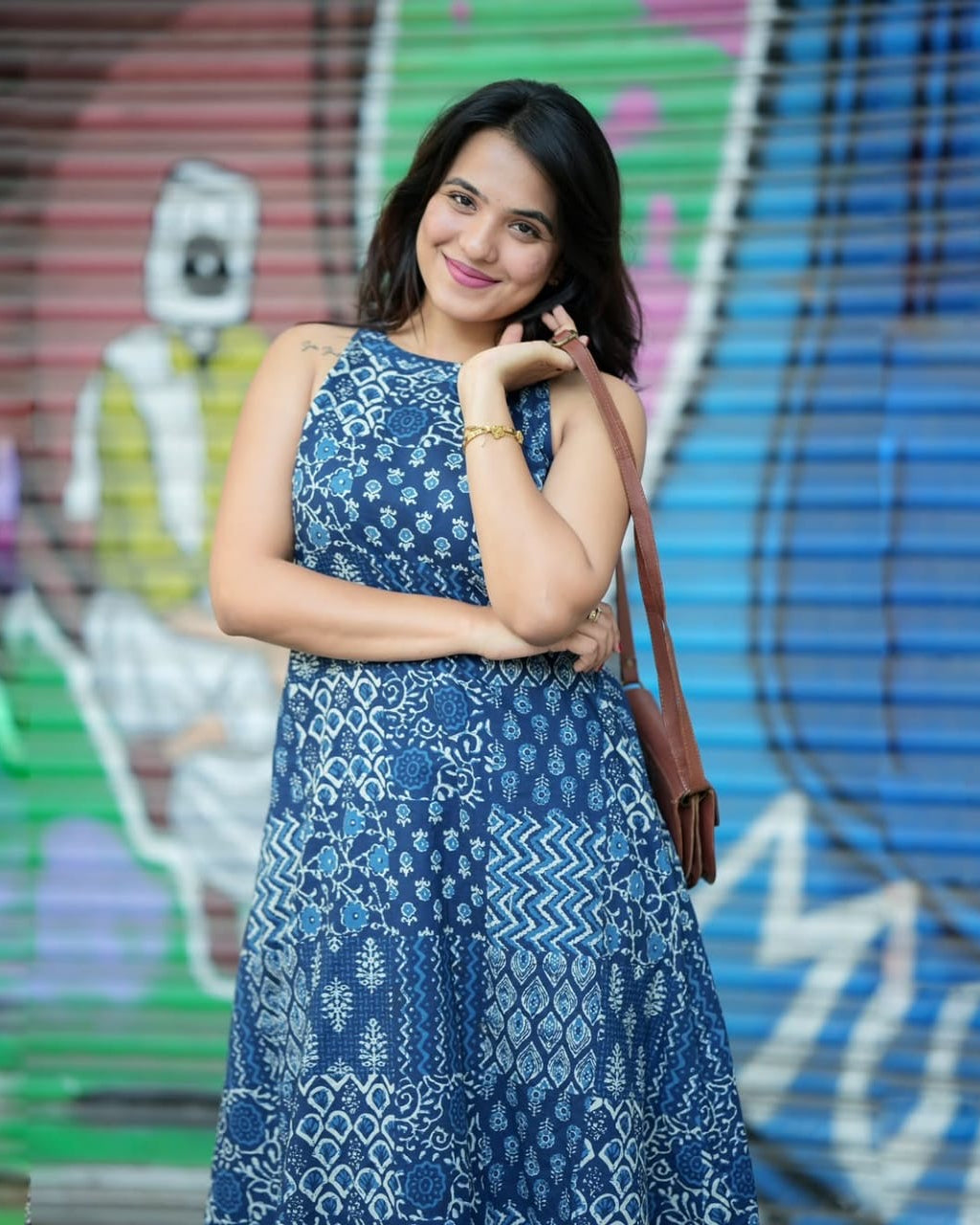 Woman in a blue patterned dress standing in front of a colorful background