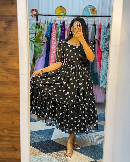 Woman in a black dress with white patterns taking a mirror selfie in a clothing store.
