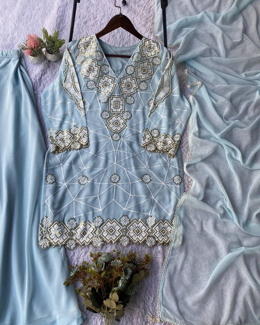 Light blue embroidered dress on a hanger with flowers and fabric in the background