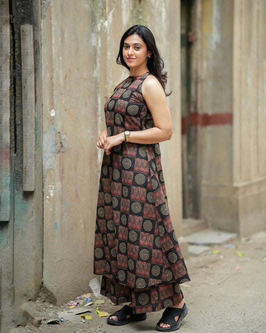 Woman wearing a patterned dress standing in an alleyway.