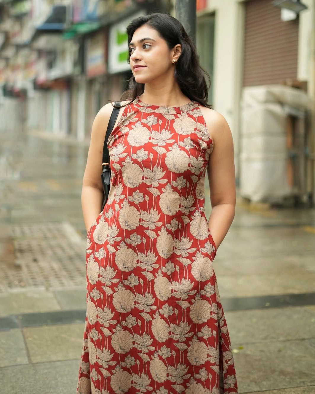 Woman wearing a red floral dress standing on a street.