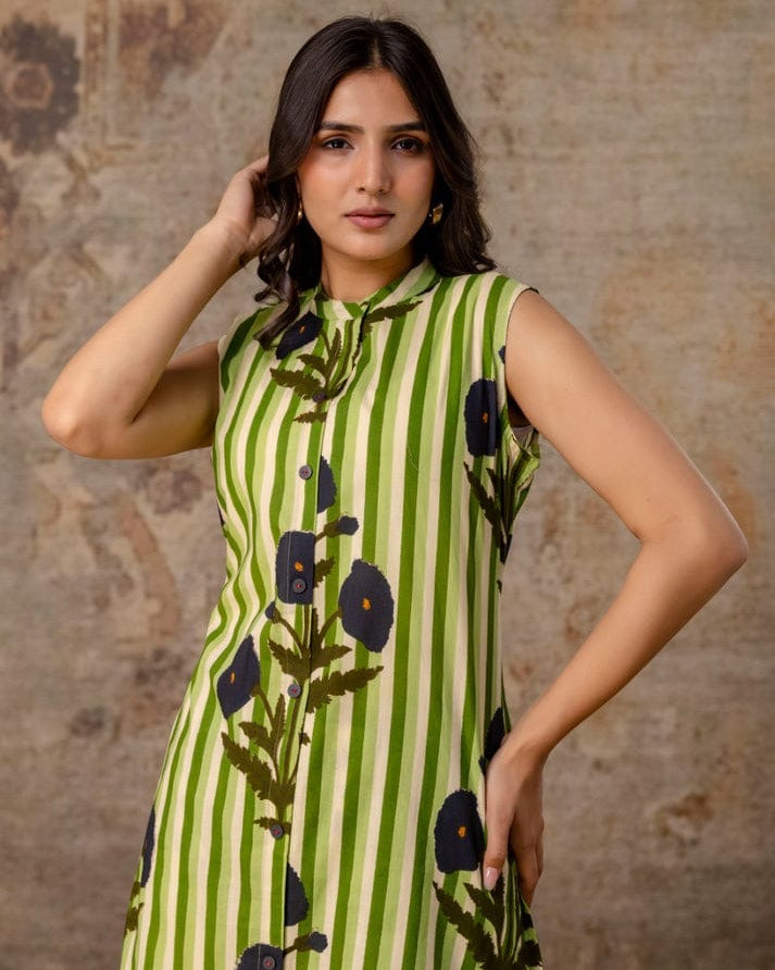 Woman wearing a green dress with floral patterns against a textured brown background
