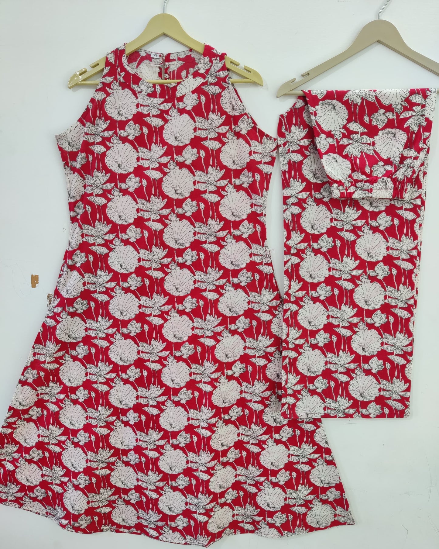 Red and white floral outfit on hangers against a white background