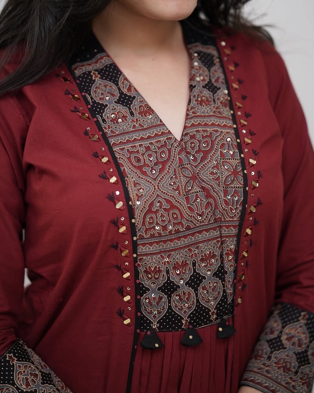 Red traditional outfit with intricate black and gold embroidery on a plain background