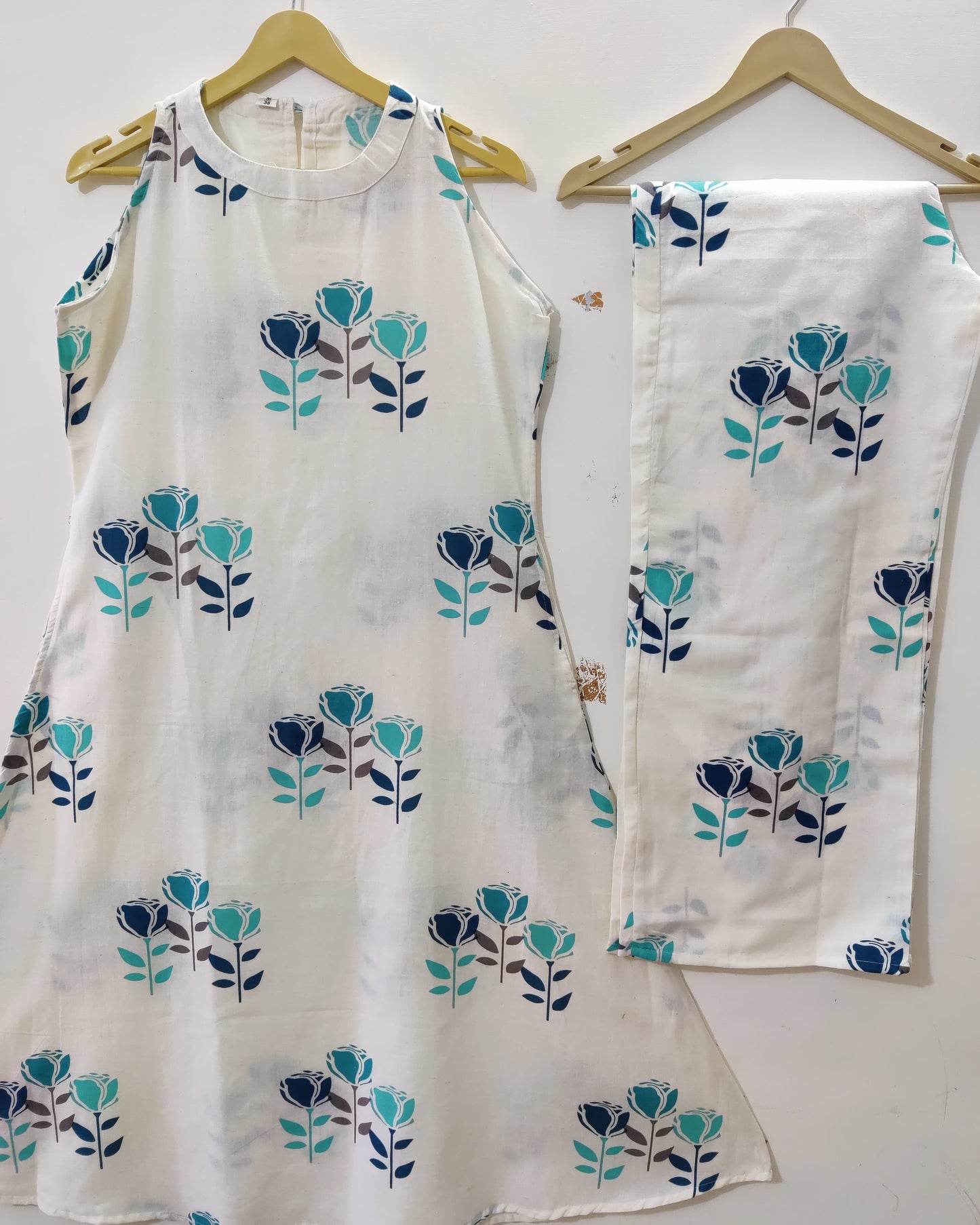 White outfit with blue floral patterns on hangers against a white background