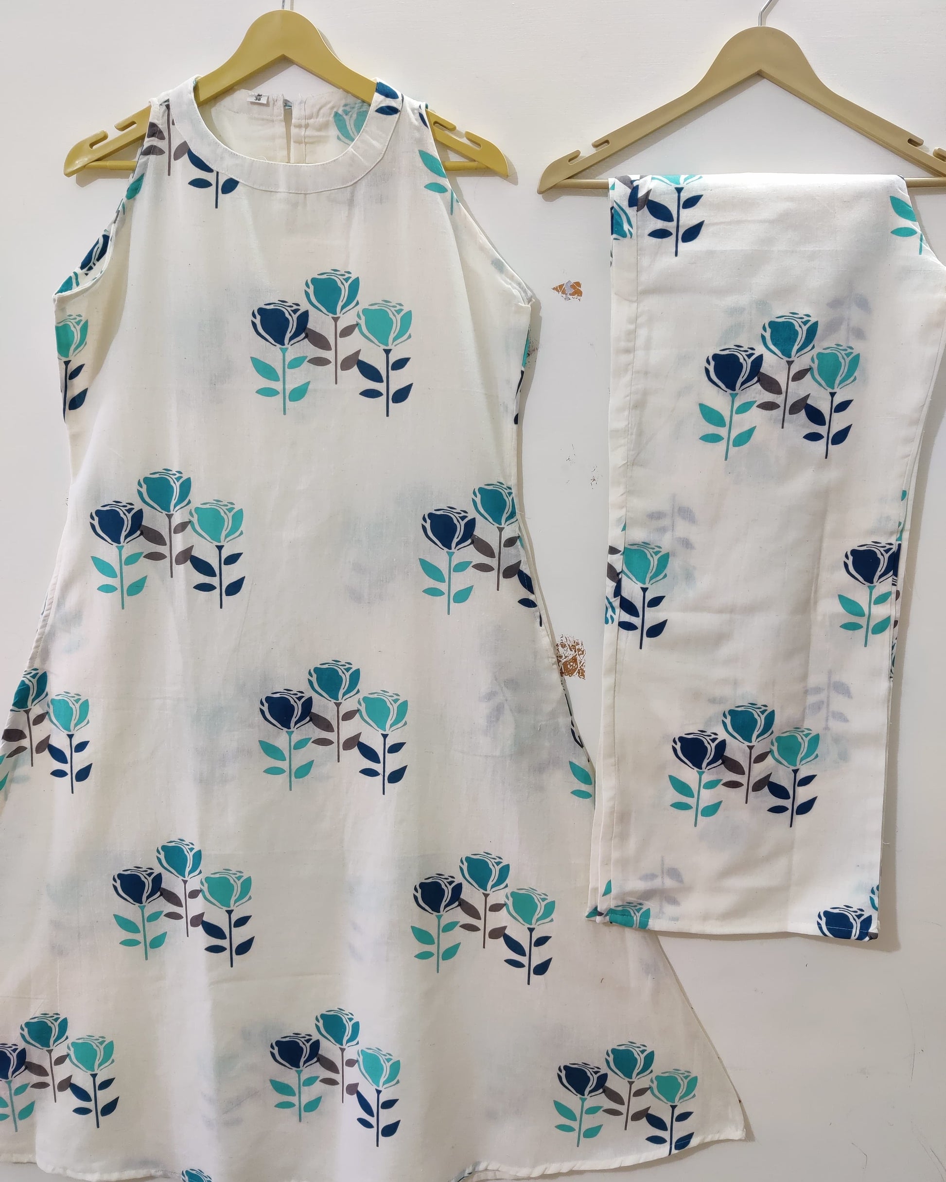 White outfit with blue floral patterns on hangers against a white background