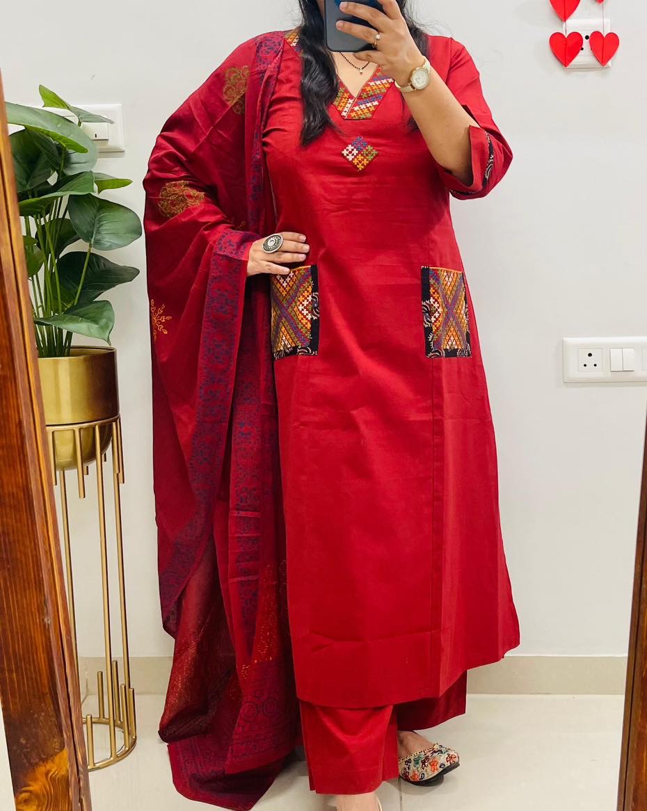 Person wearing a red traditional outfit with intricate patterns indoors.