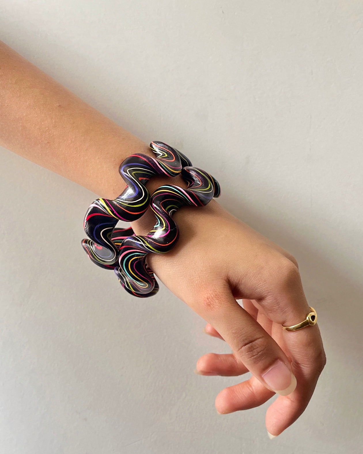 Hand wearing a colorful bracelet on a plain background