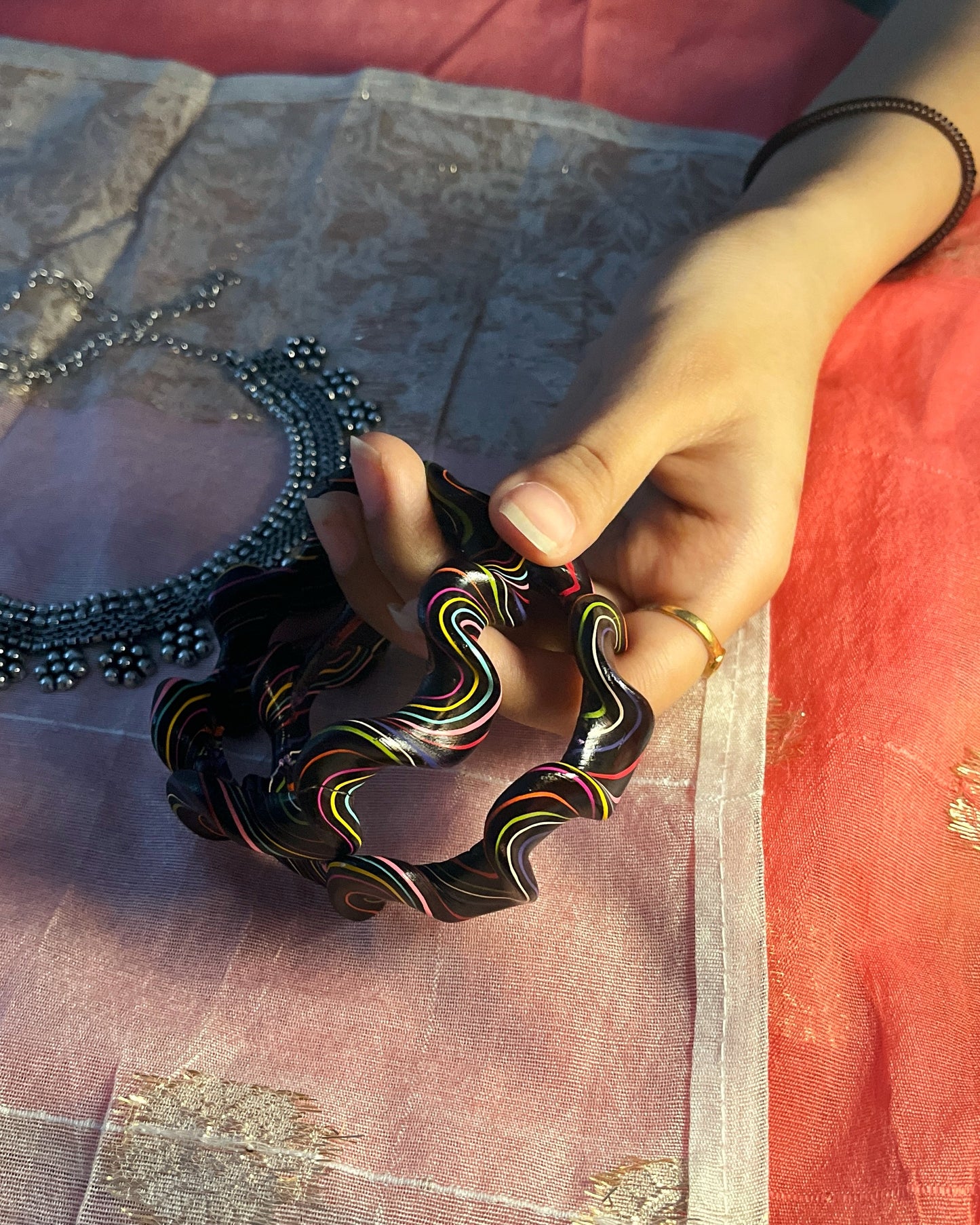Hand holding a colorful bracelet on a textured fabric background