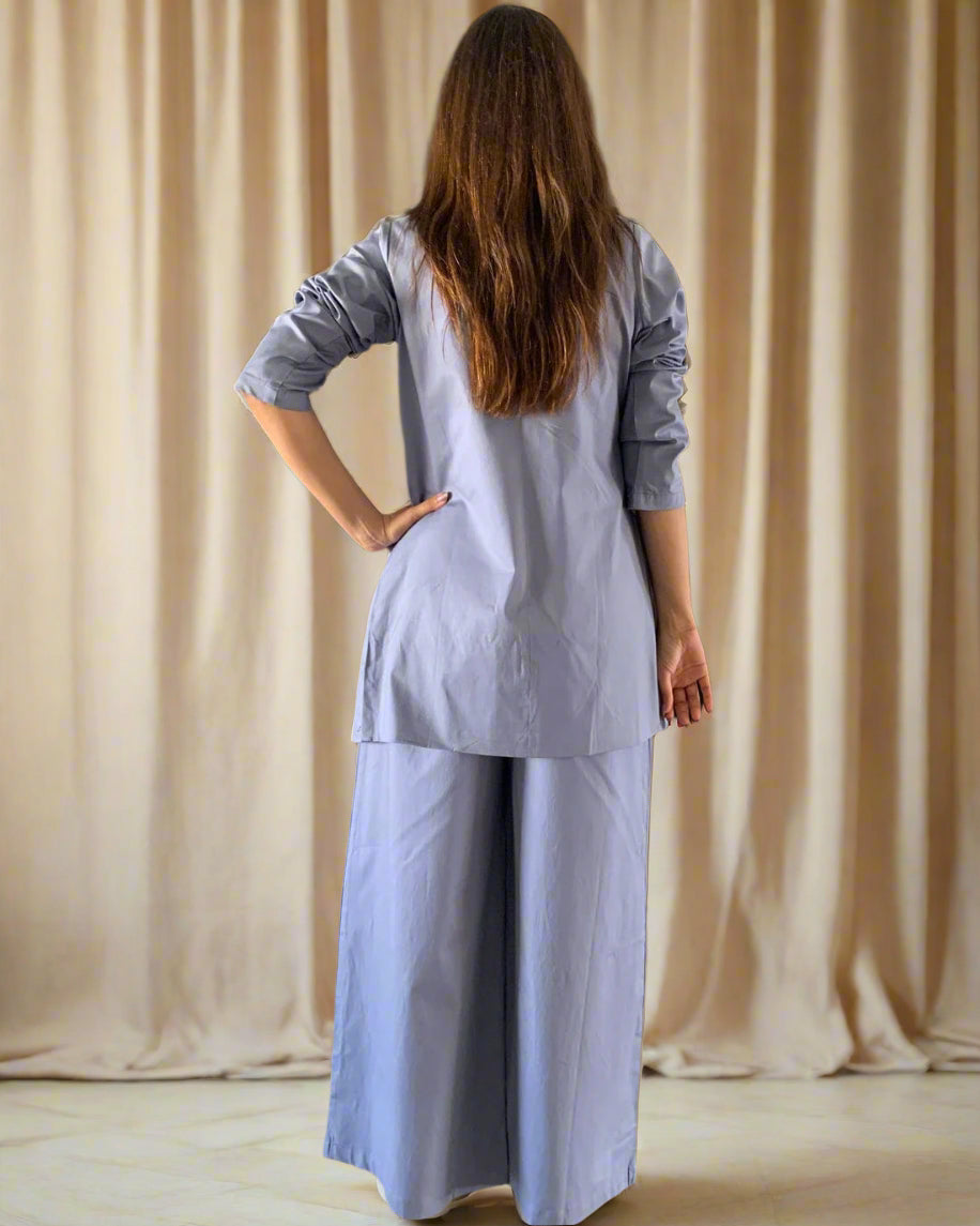Person wearing a light blue outfit standing in a room with decorative elements.