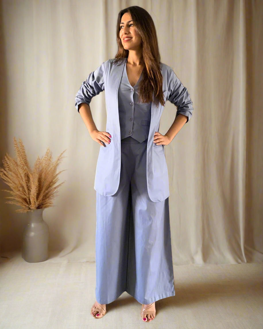 Woman in a light blue outfit standing in a room with wooden flooring and decorative elements.