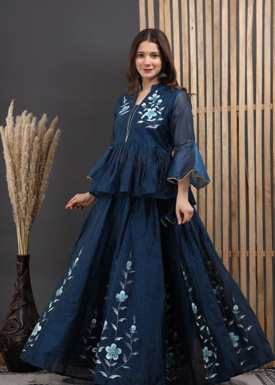 Woman wearing a dark blue embroidered dress against a neutral background
