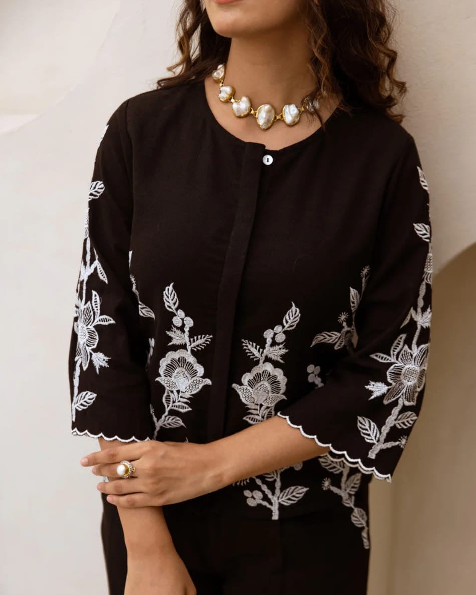 Black embroidered jacket worn by a person against a neutral background